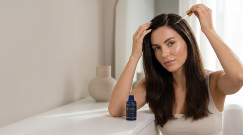 Woman applying Emvia GHK-Cu hair serum to scalp